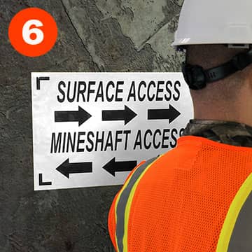 Directional sign adhered to a rough mine surface