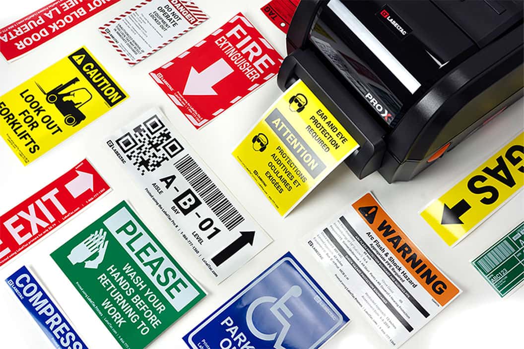 LabelTac Pro X printer surrounded by printed safety label samples