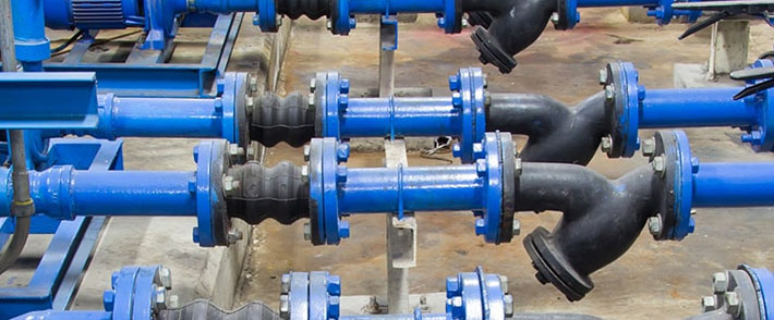 Blue industrial piping system with flanged connections, rubber expansion joints, and angled Y-strainer fittings