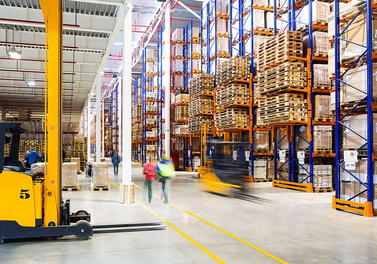 Warehouse aisle with yellow SafetyTac floor tape lanes and forklift